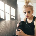 Young teenage girl dancer crying after loss perfomance sit on cube decoration in dance studio