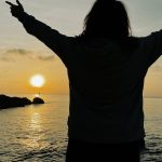 a person standing on a beach with their arms outstretched